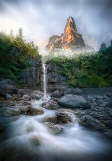 Beautiful mountain, waterfall, trees, and river with rocks in Dolomites