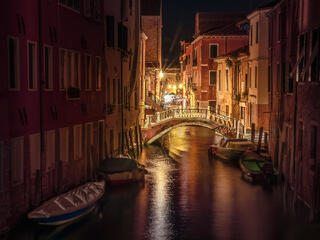 Venice night after sunset on canal with boats and bridge,  night lights and houses
